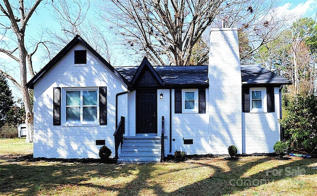 view of front of property featuring a front lawn, a chimney, brick siding, and crawl space