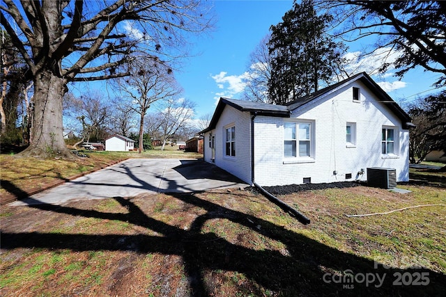 view of side of home featuring cooling unit, brick siding, and crawl space