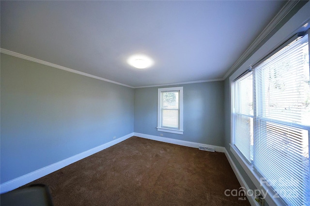 empty room with visible vents, crown molding, baseboards, and dark colored carpet