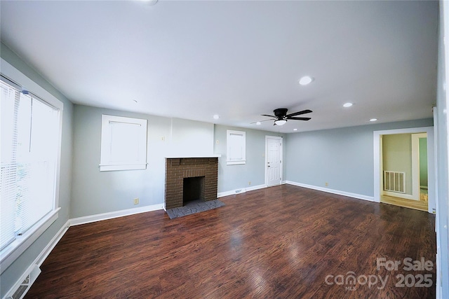 unfurnished living room with visible vents, baseboards, dark wood-style floors, and a fireplace