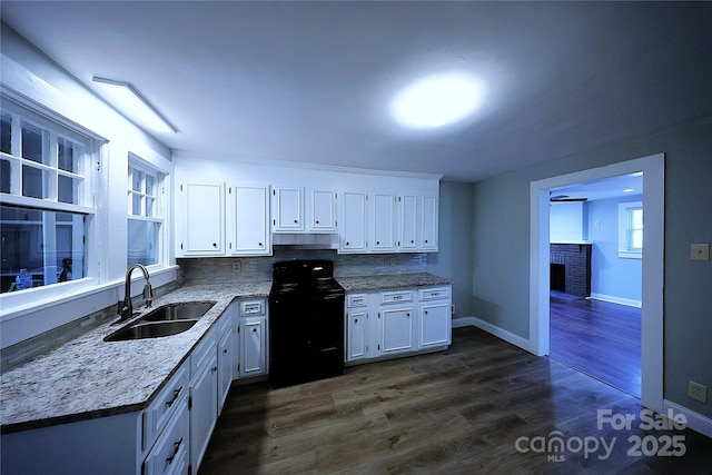 kitchen with under cabinet range hood, black electric range, white cabinets, and a sink