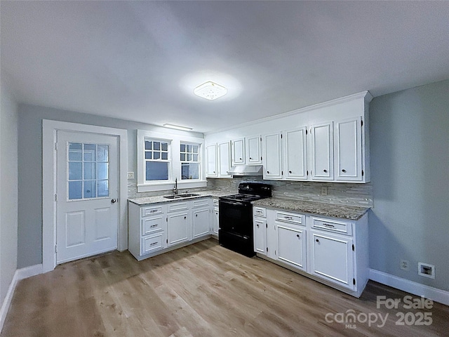 kitchen featuring light wood finished floors, backsplash, under cabinet range hood, black electric range oven, and a sink