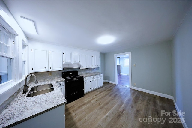 kitchen with wood finished floors, a sink, black range with electric cooktop, under cabinet range hood, and white cabinetry