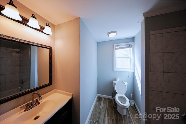 bathroom featuring a shower, toilet, vanity, and baseboards