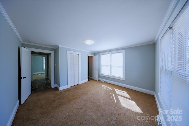 unfurnished bedroom with crown molding, visible vents, baseboards, and carpet floors