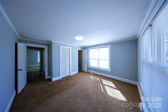 unfurnished bedroom featuring carpet flooring, two closets, baseboards, and ornamental molding