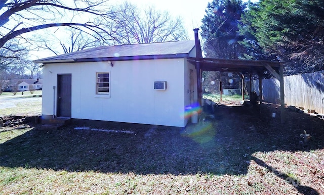 view of outbuilding with an attached carport, driveway, and fence