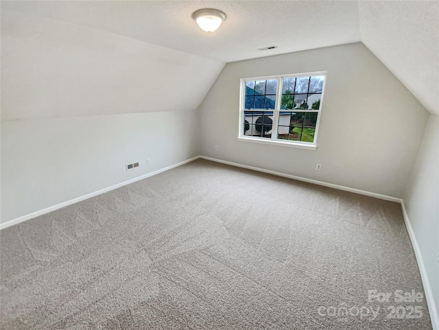 additional living space with baseboards, carpet floors, and a textured ceiling