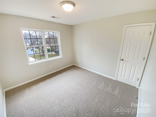 carpeted spare room featuring visible vents, a textured ceiling, and baseboards