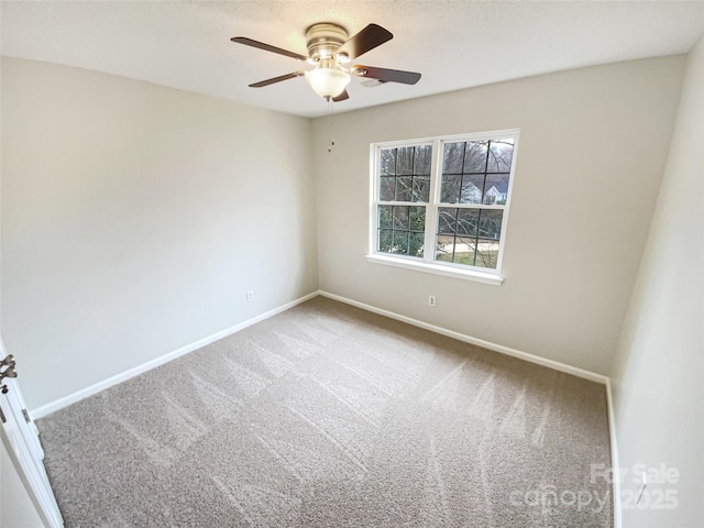 carpeted spare room with a ceiling fan and baseboards