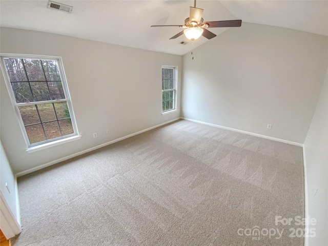 empty room with visible vents, carpet floors, lofted ceiling, and a healthy amount of sunlight