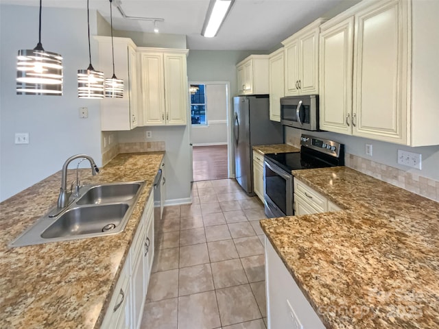 kitchen featuring light tile patterned floors, a peninsula, a sink, appliances with stainless steel finishes, and pendant lighting