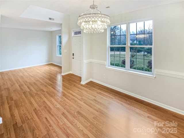 empty room with baseboards, visible vents, a chandelier, and light wood-type flooring