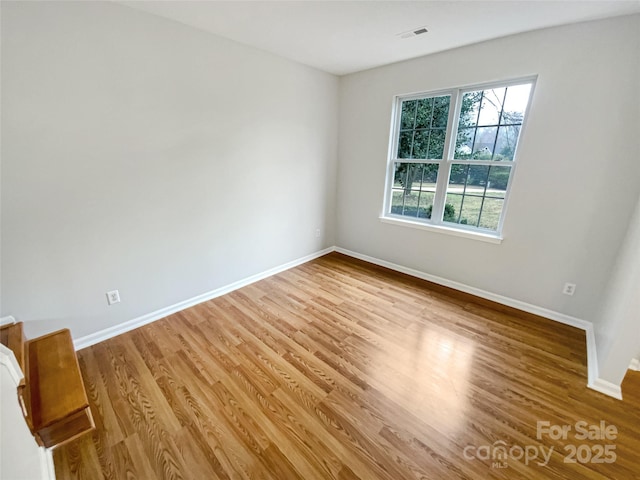 unfurnished room with visible vents, baseboards, and wood finished floors