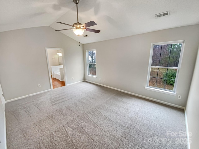 carpeted empty room with visible vents, baseboards, and lofted ceiling