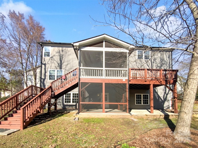 rear view of house featuring stairway, a sunroom, a yard, a deck, and a patio area