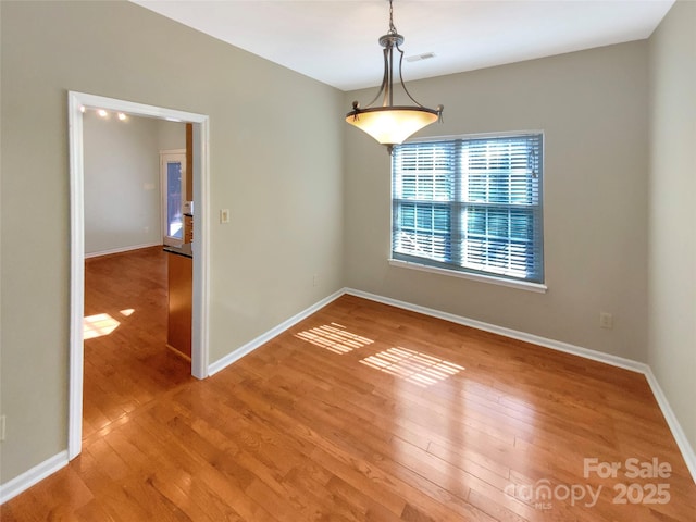 unfurnished room with visible vents, light wood-style floors, and baseboards