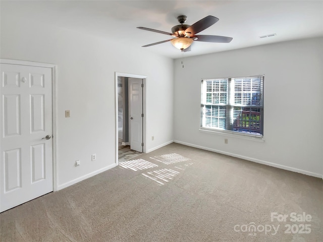 unfurnished bedroom featuring visible vents, ensuite bath, carpet, baseboards, and ceiling fan