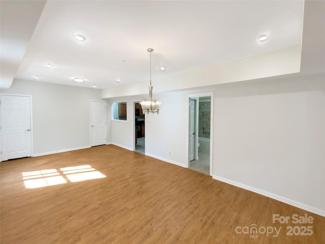 unfurnished room with recessed lighting, baseboards, an inviting chandelier, and wood finished floors