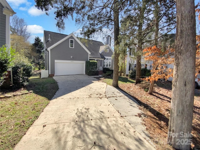 view of front facade featuring concrete driveway, a chimney, and a garage