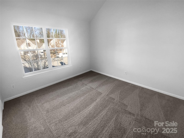 unfurnished room with lofted ceiling, baseboards, and dark carpet