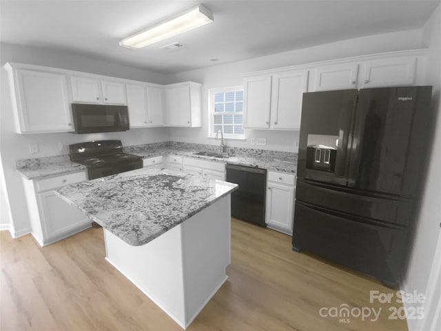 kitchen with a sink, black appliances, and white cabinetry