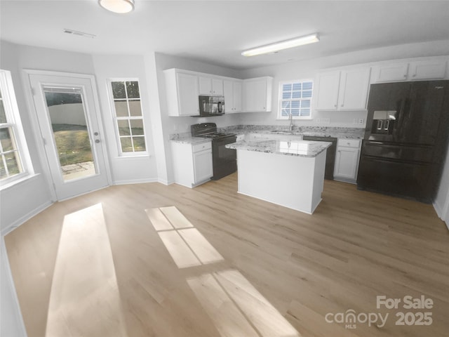 kitchen featuring visible vents, a healthy amount of sunlight, black appliances, white cabinetry, and a sink