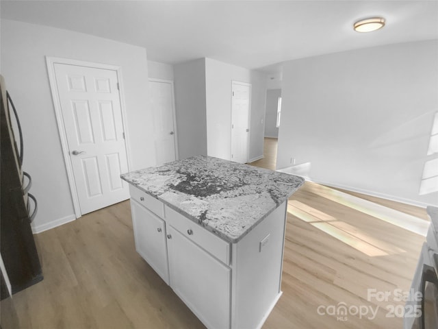 kitchen with light stone counters, baseboards, white cabinetry, light wood-type flooring, and a center island