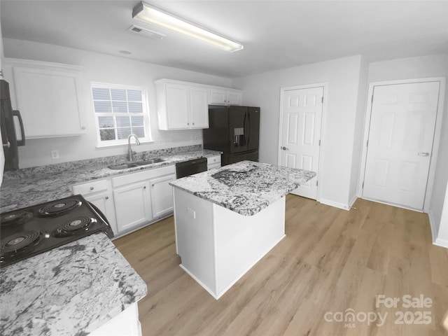 kitchen with a sink, visible vents, black appliances, and white cabinetry