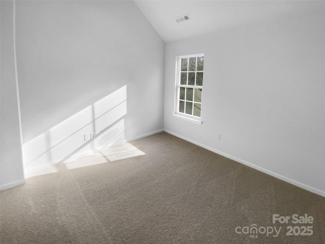 empty room featuring carpet flooring, baseboards, visible vents, and vaulted ceiling