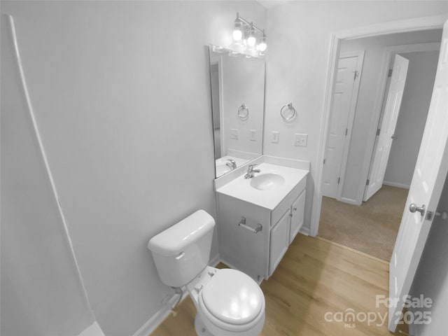 bathroom featuring vanity, toilet, wood finished floors, and baseboards