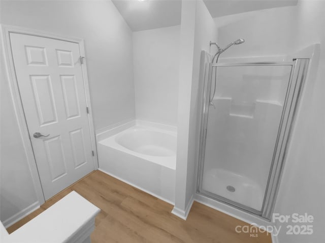 full bath with a bath, wood finished floors, and a stall shower