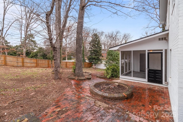 view of yard featuring a patio area, a fenced backyard, and a sunroom