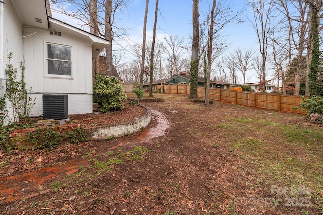 view of yard with central air condition unit and fence