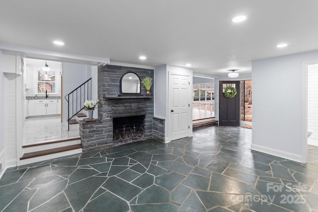 living area with a stone fireplace, recessed lighting, and stairway