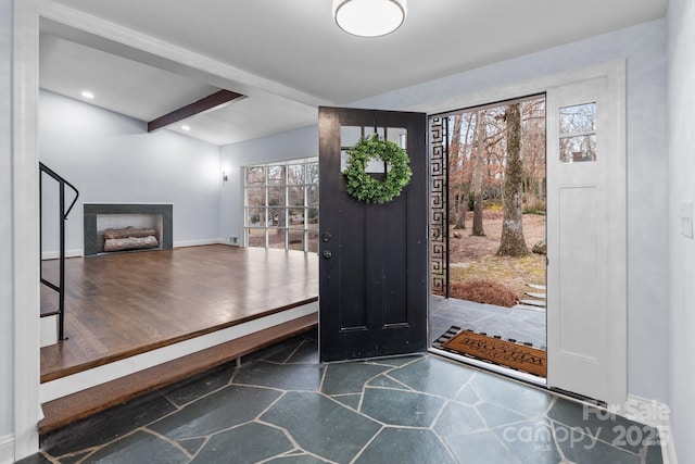 entryway featuring beamed ceiling, plenty of natural light, a fireplace, and baseboards