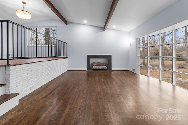 unfurnished living room with wood finished floors, vaulted ceiling with beams, a fireplace, and baseboards