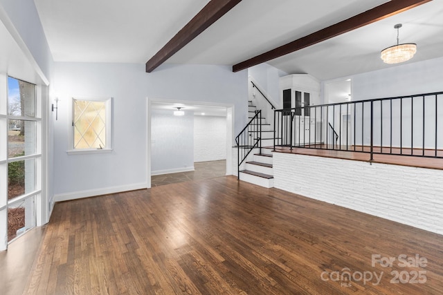 unfurnished living room featuring beam ceiling, wood finished floors, stairway, an inviting chandelier, and baseboards