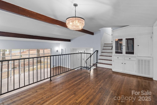 empty room featuring beam ceiling, dark wood-type flooring, stairway, and a chandelier