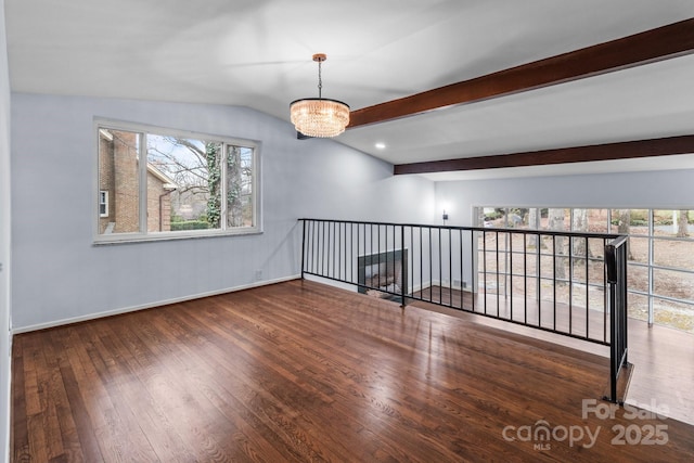 empty room with a notable chandelier, a healthy amount of sunlight, vaulted ceiling with beams, and hardwood / wood-style flooring