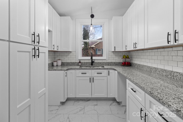 kitchen with white cabinetry, decorative backsplash, marble finish floor, and a sink