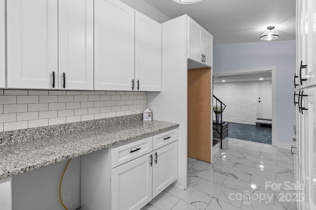 kitchen with decorative backsplash, marble finish floor, white cabinetry, and light stone countertops