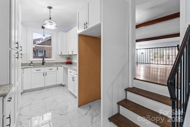 kitchen featuring marble finish floor, light stone counters, tasteful backsplash, white cabinetry, and hanging light fixtures