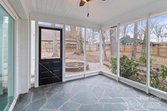 unfurnished sunroom featuring wooden ceiling and a ceiling fan