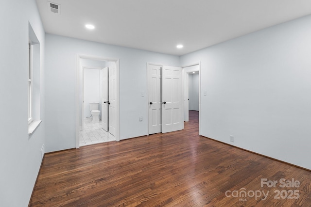 unfurnished bedroom featuring ensuite bath, recessed lighting, wood finished floors, and visible vents