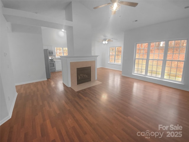 unfurnished living room with visible vents, a healthy amount of sunlight, wood finished floors, and a tile fireplace