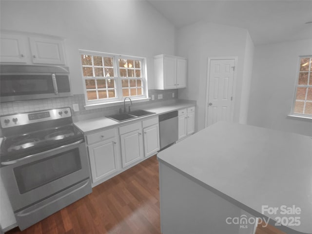 kitchen featuring dark wood-style floors, a sink, decorative backsplash, white cabinets, and appliances with stainless steel finishes