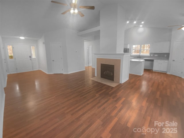 unfurnished living room featuring high vaulted ceiling, a ceiling fan, a tiled fireplace, baseboards, and dark wood-style flooring