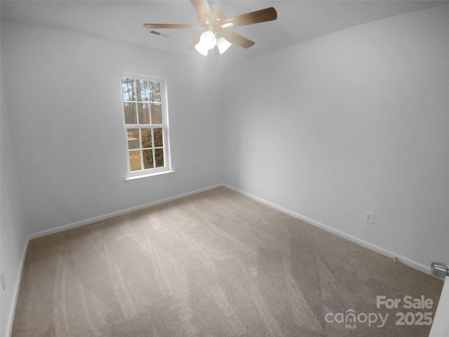 carpeted empty room with visible vents, a ceiling fan, and baseboards