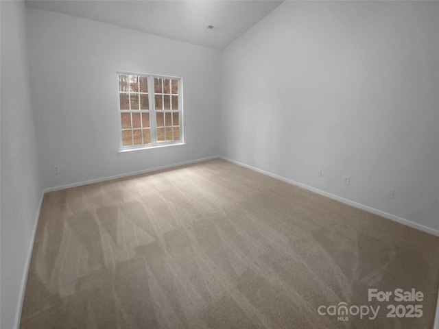 carpeted empty room with lofted ceiling and baseboards